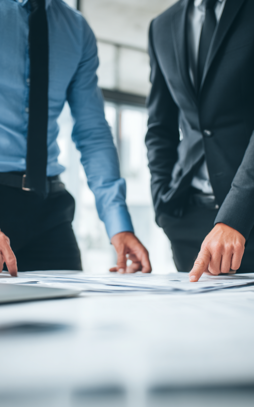 u2382843823_Two_businessmen_standing_at_a_desk_reviewing_docu_91c92726-cd1c-448e-9222-0d750e04e161_0